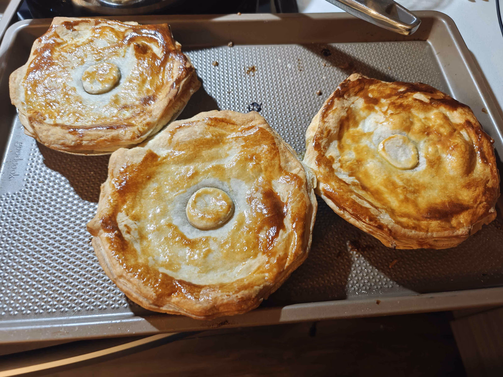 A tray of chicken pot pies fresh from the oven, golden and glossy